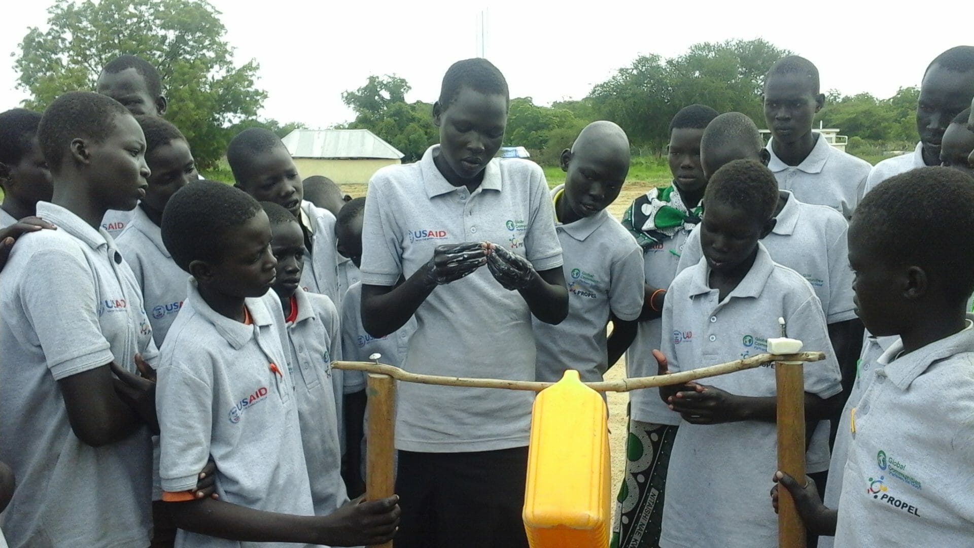 children looking at a basic handwashing system